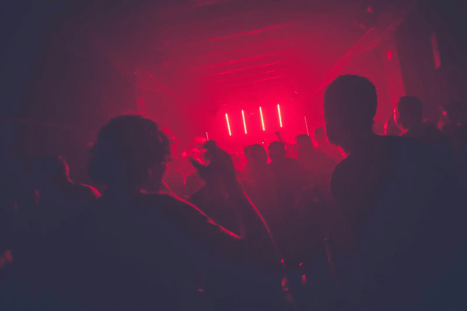 Crowd dancing under neon lights at a late-night deep house event